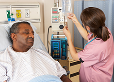Nurse Checking Senior Male Patient's IV Drip On Ward
