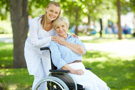 Home health aide in Boynton Beach, FL, walking with senior woman in a wheelchair at a park